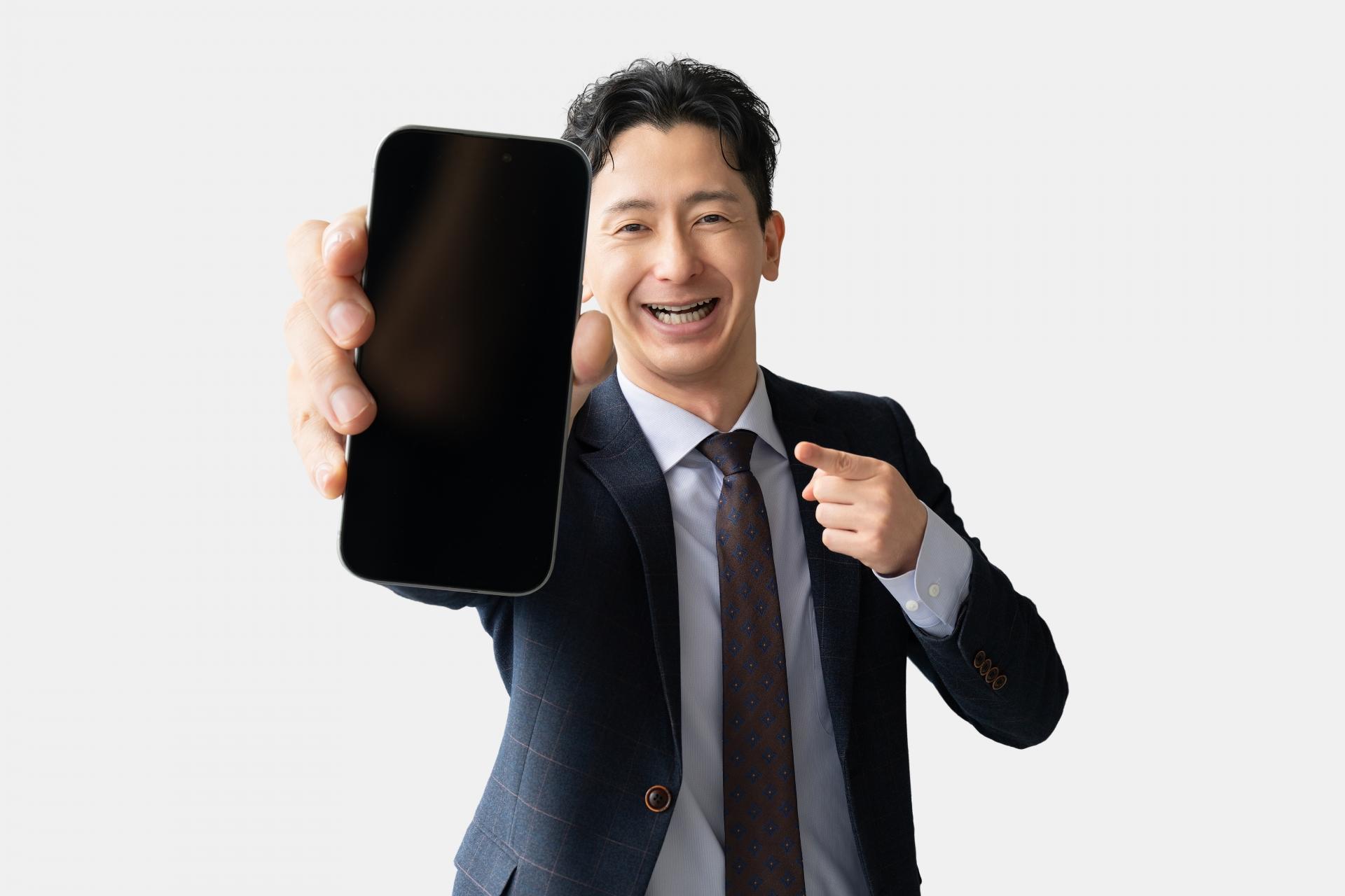 スマートフォンの画面を見せるスーツ姿の男性