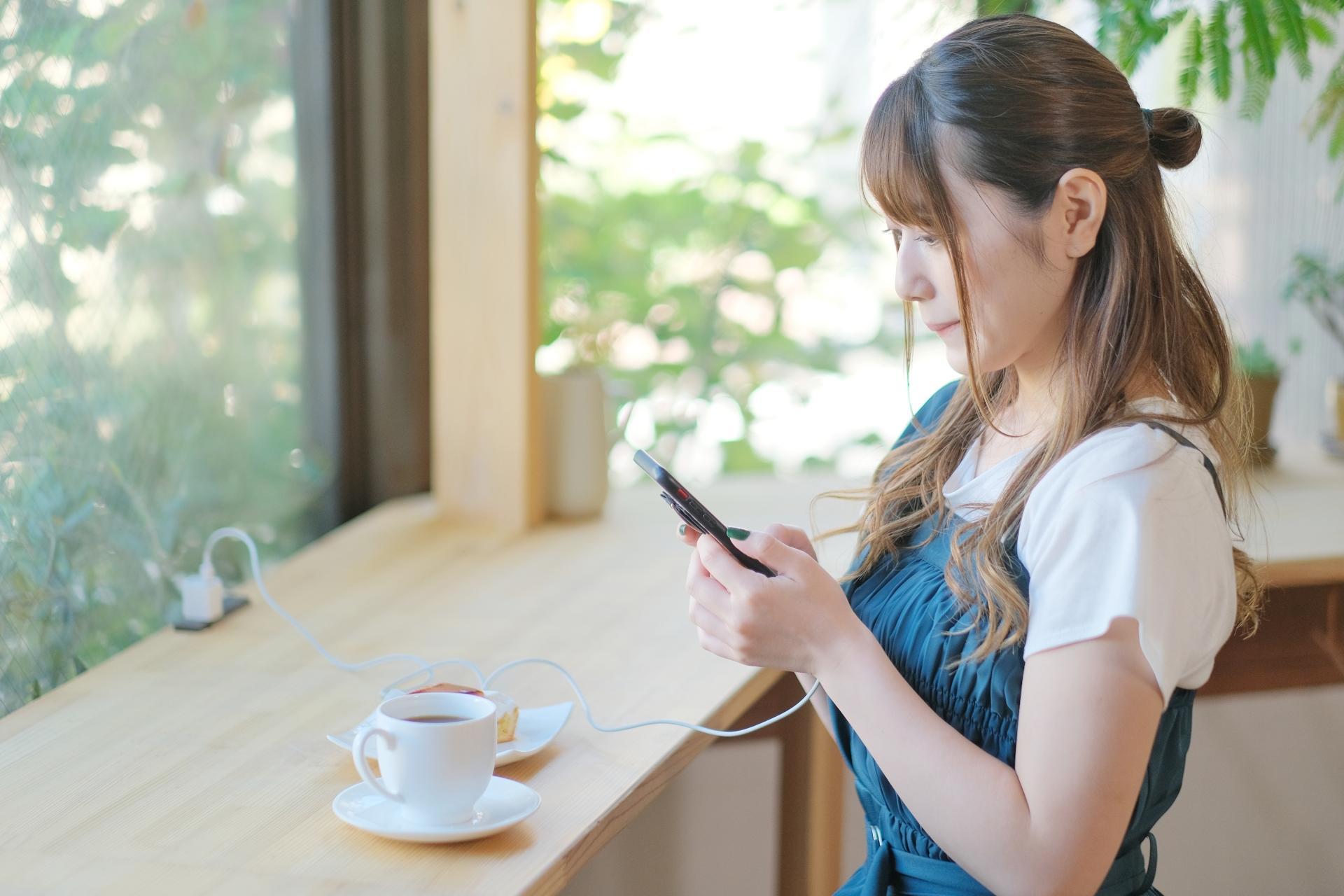 カフェでスマートフォンを使う女性