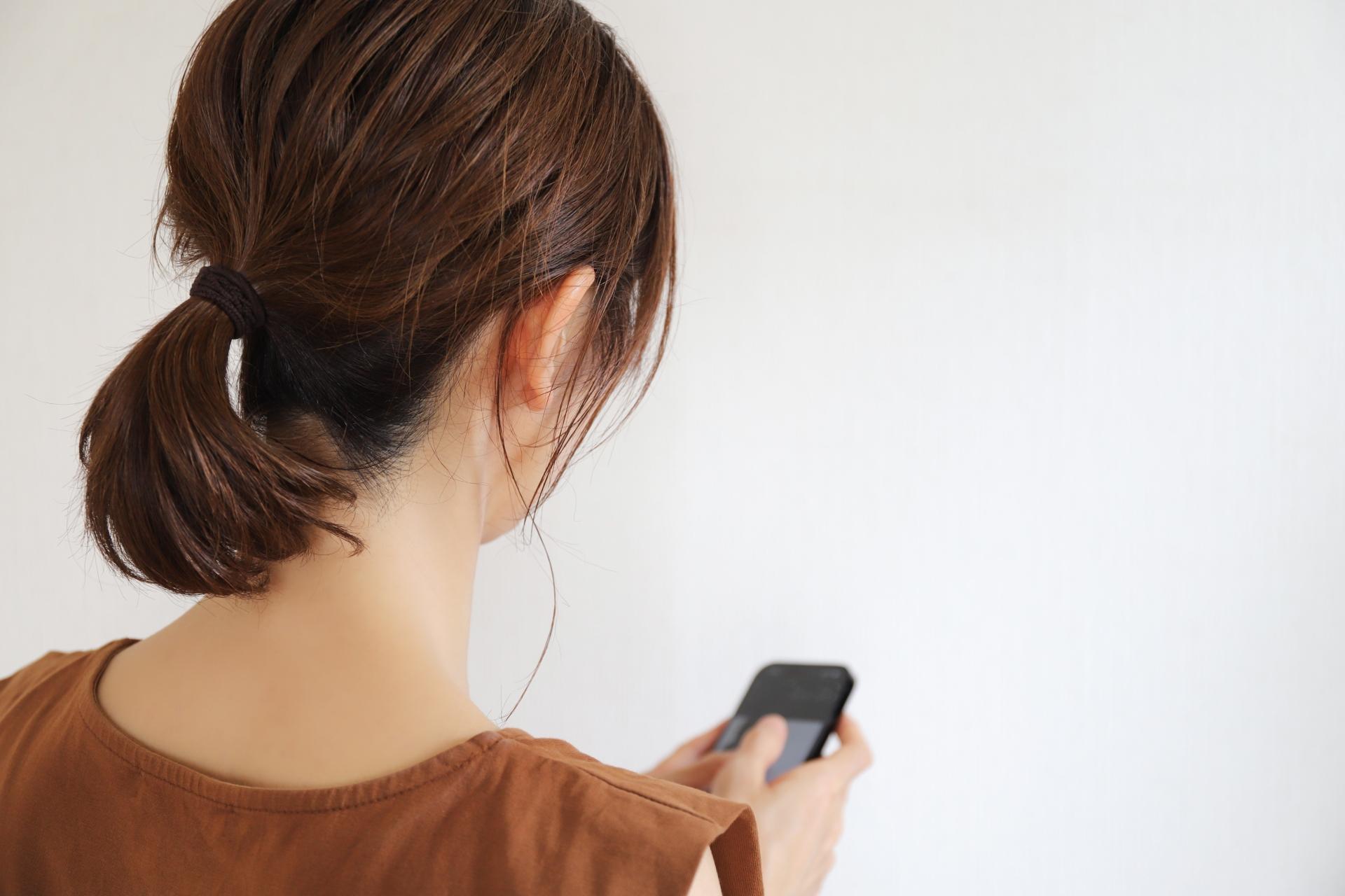 スマートフォンを持つ女性の後ろ姿