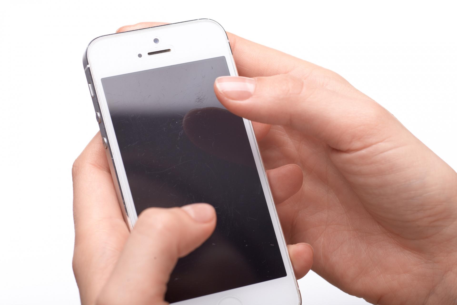 スマートフォンの画面を指で操作する手元