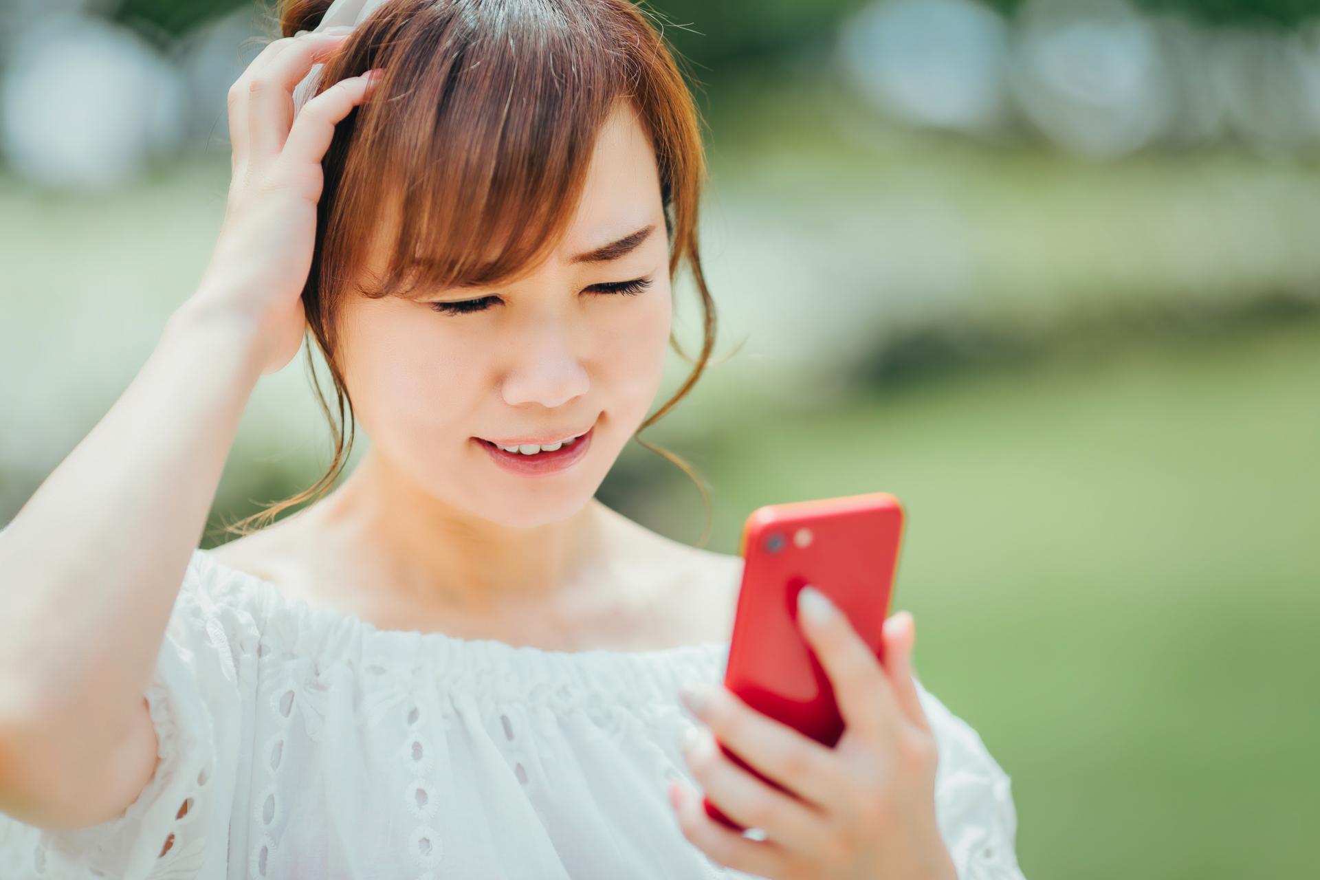 屋外でスマートフォンを見て困る女性