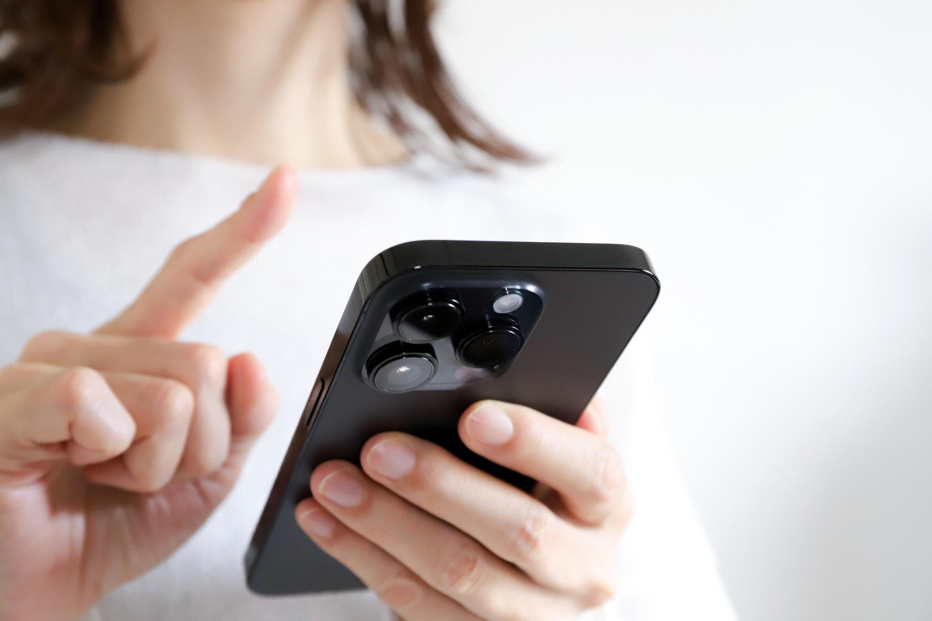 スマートフォンを指で操作する女性の手元