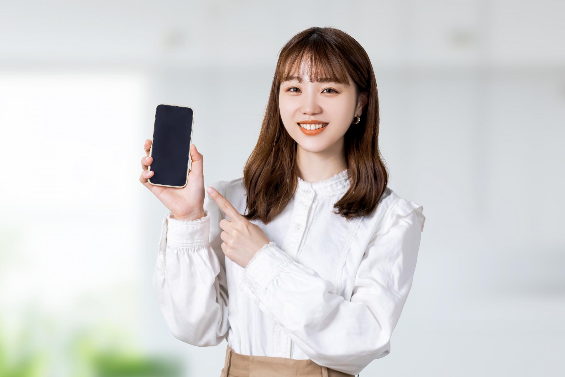 スマートフォンの画面を見せる女性