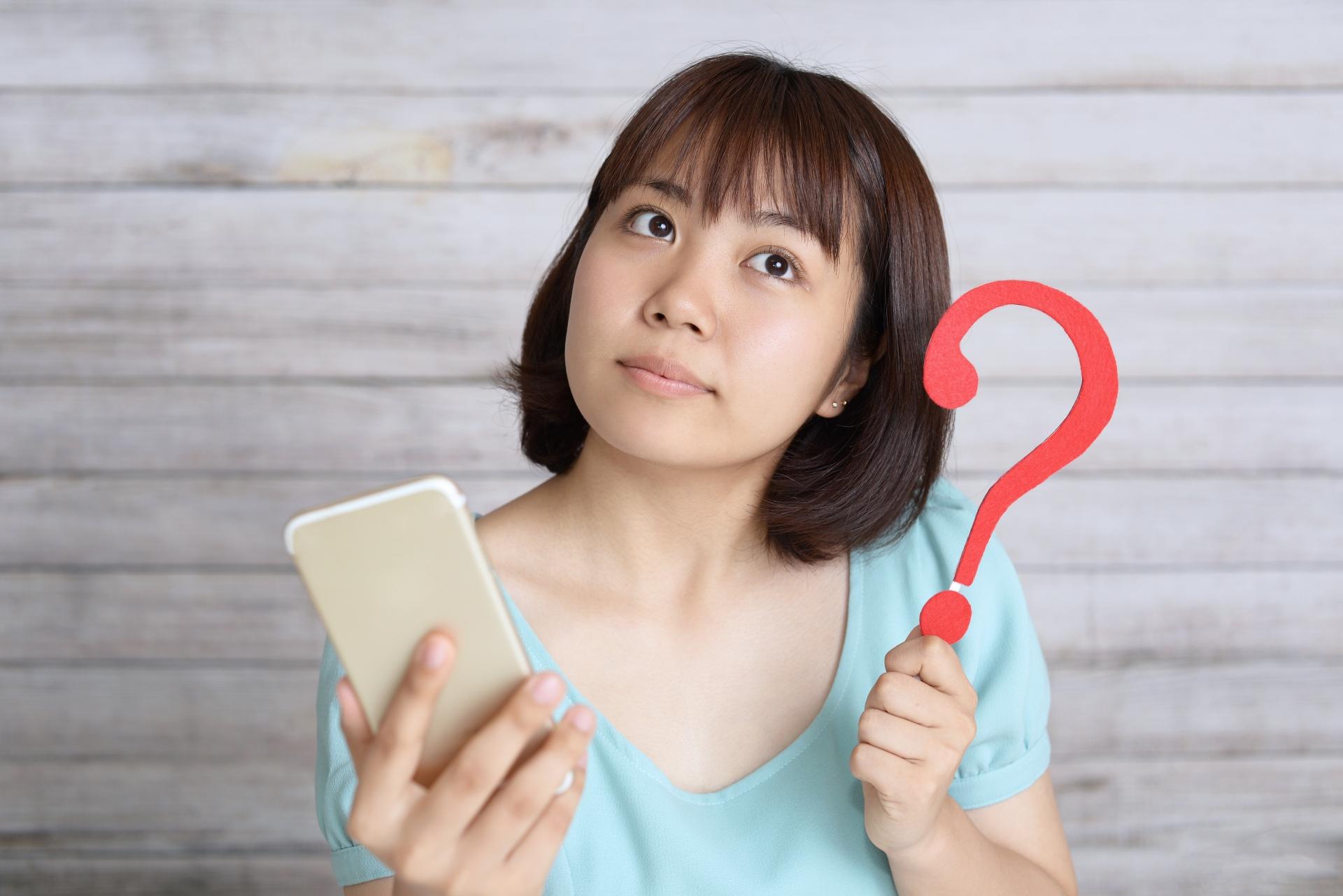 スマートフォンと疑問符を持つ女性