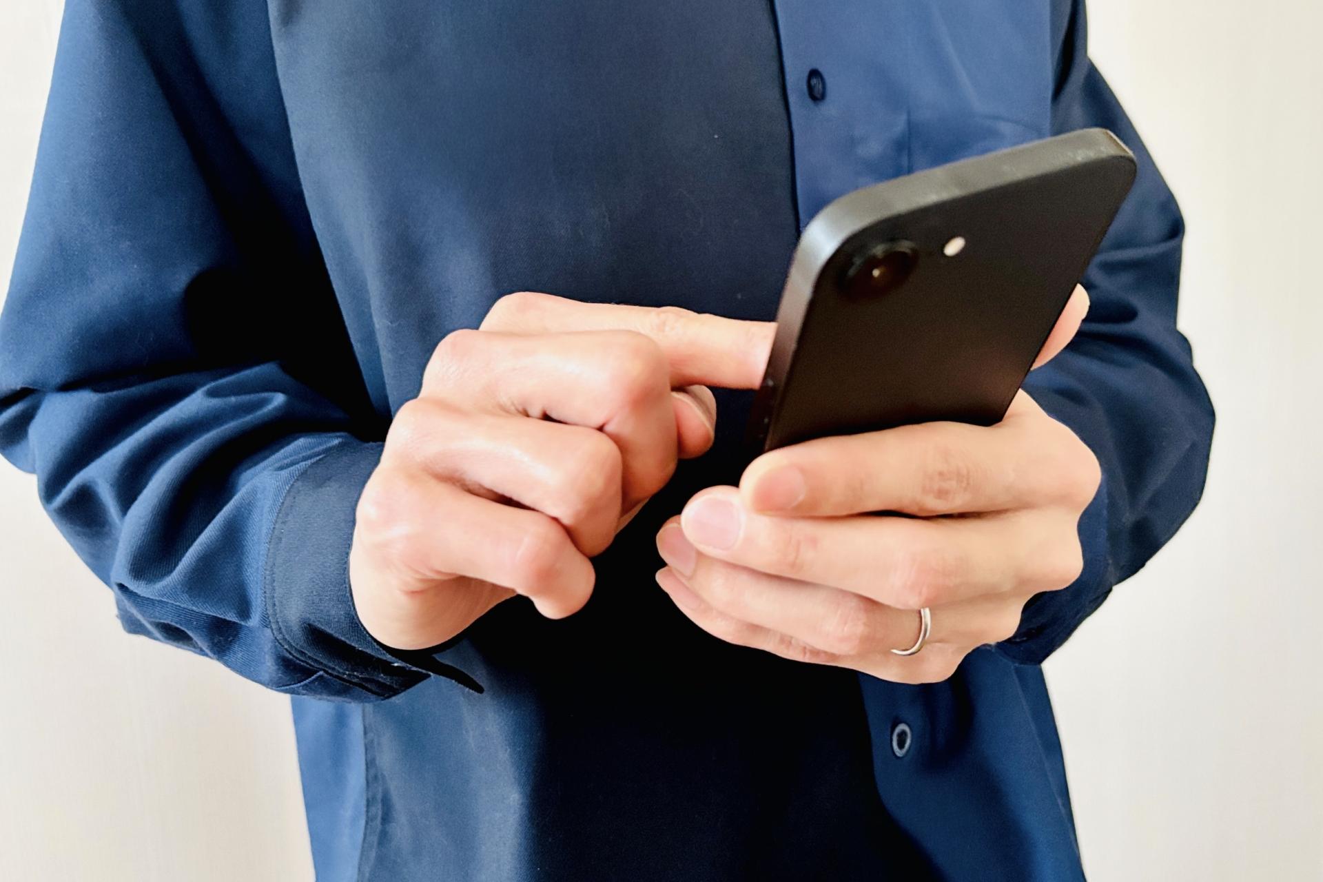 スマートフォンを操作する男性の手元