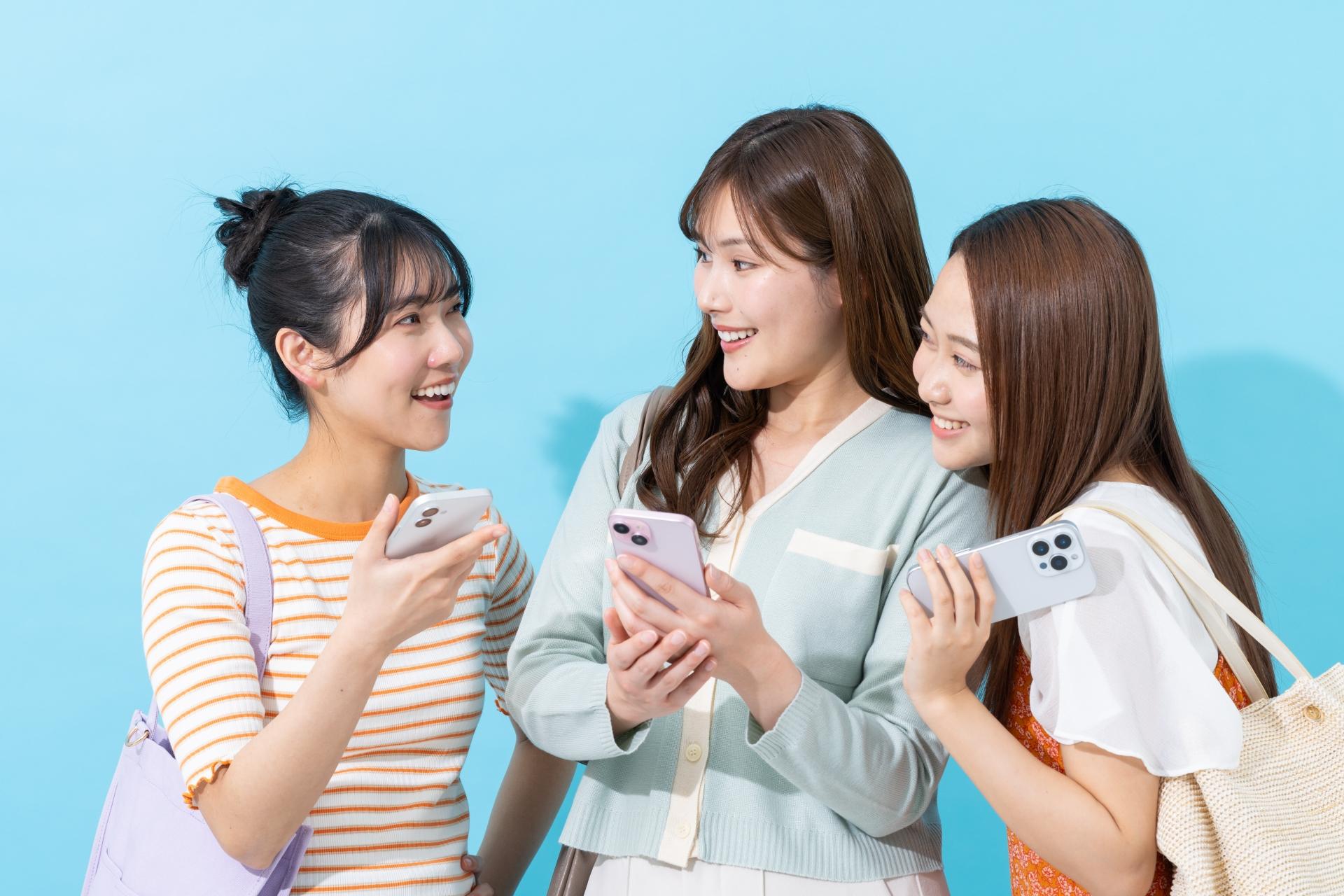 スマートフォンを持ちながら話す3人の女性