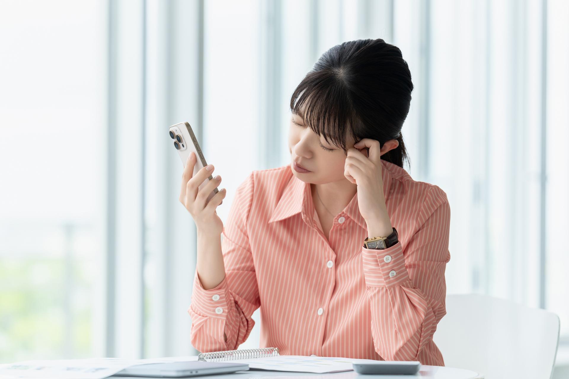 スマートフォンを手に悩む女性